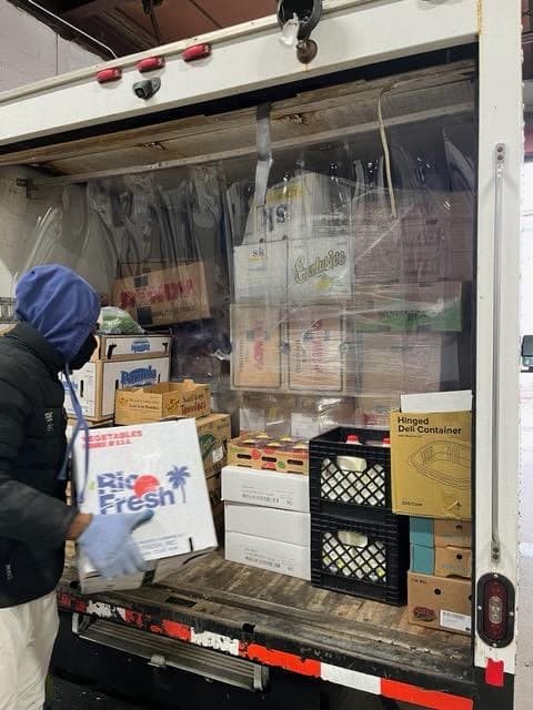 A team member loading fresh produce onto a Supreme delivery truck